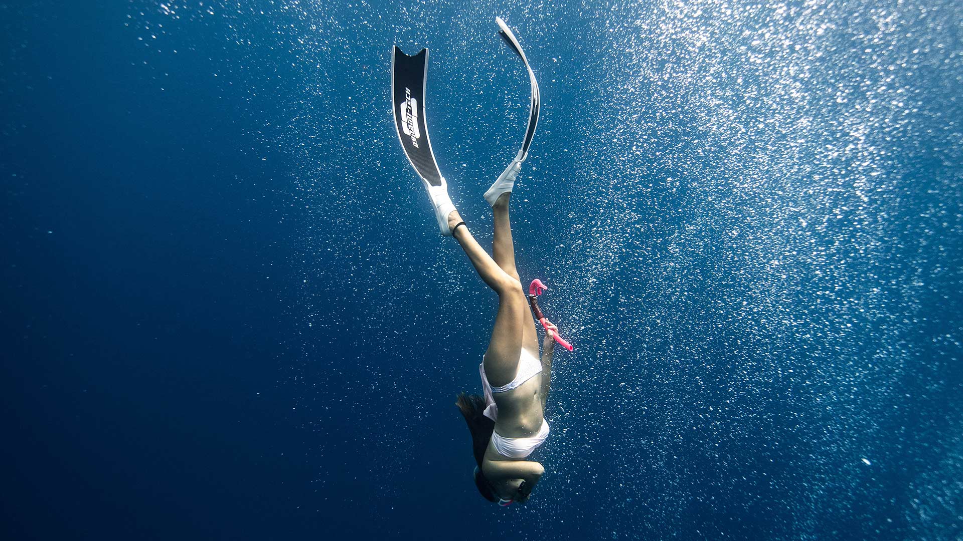 Chica con aletas de buceo, sumergiéndose mientras hace buceo en Almería